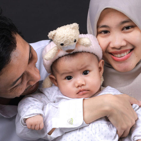 Young family indoor portrait with black background